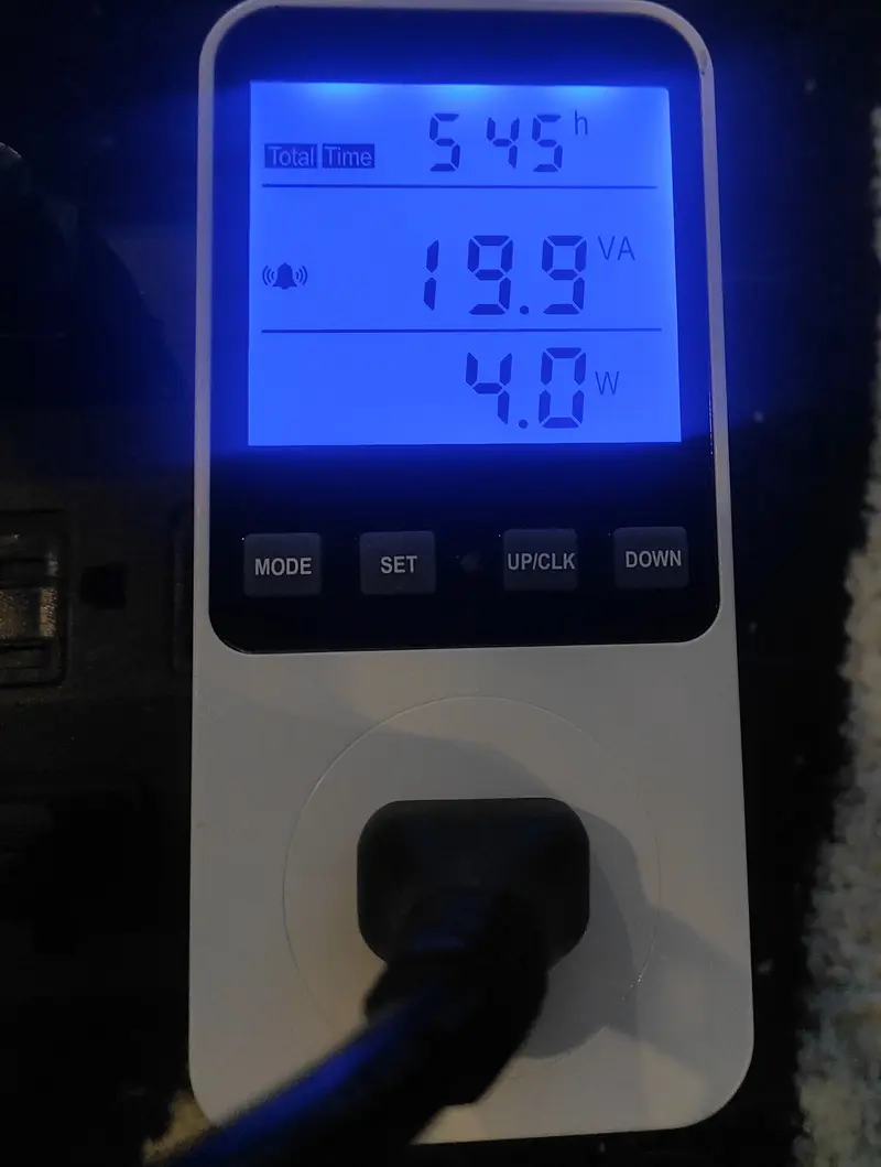A photograph of an electricity consumption meter plugged into an outlet. The meter’s display shows apparent power consumption of 19.9 VA, and a real power consumption reading of 4.0 Watts, indicating a very low power draw scenario.